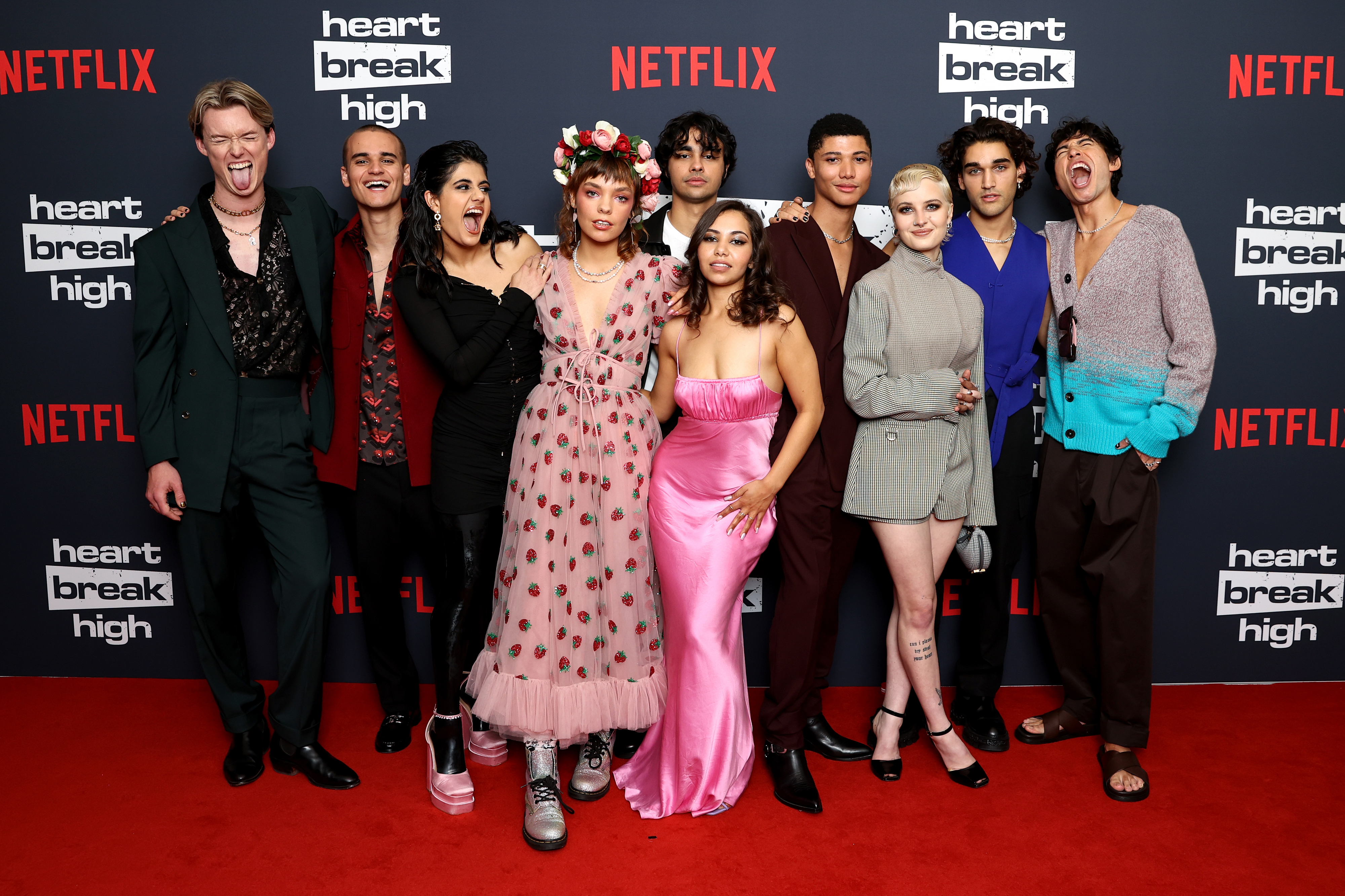 Cast members of a show posing together on a red carpet event