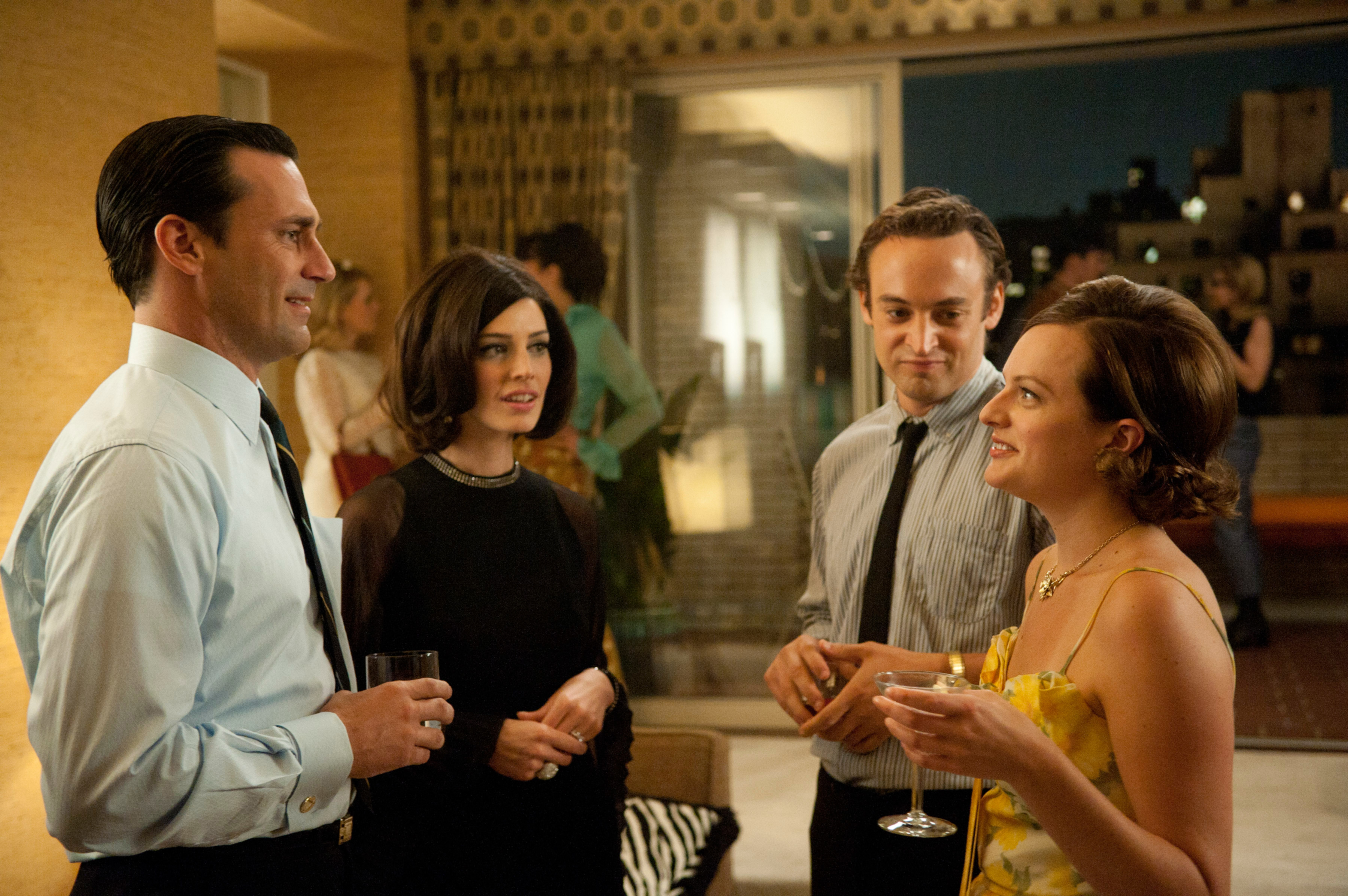 Four characters from a TV show in a social gathering, holding drinks and conversing
