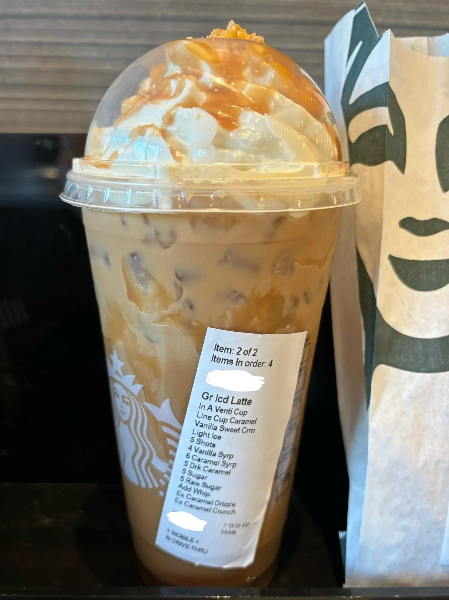 Iced latte with caramel drizzle in a clear cup, custom order sticker visible