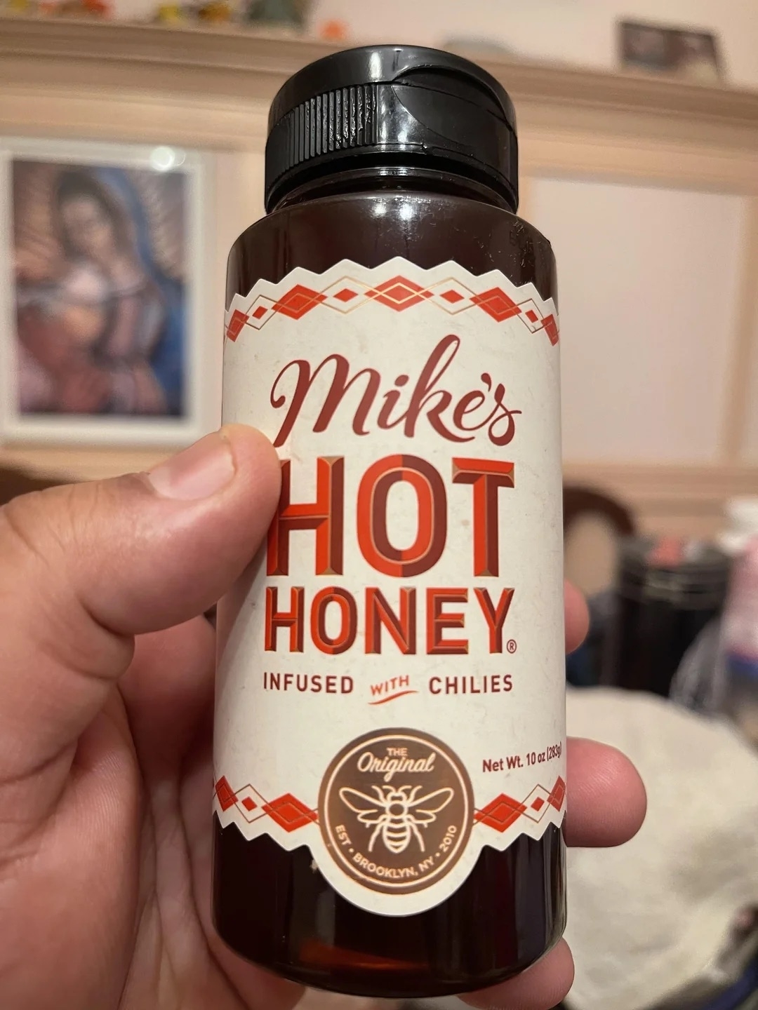 A person holding a bottle of Mike&#x27;s Hot Honey infused with chilies