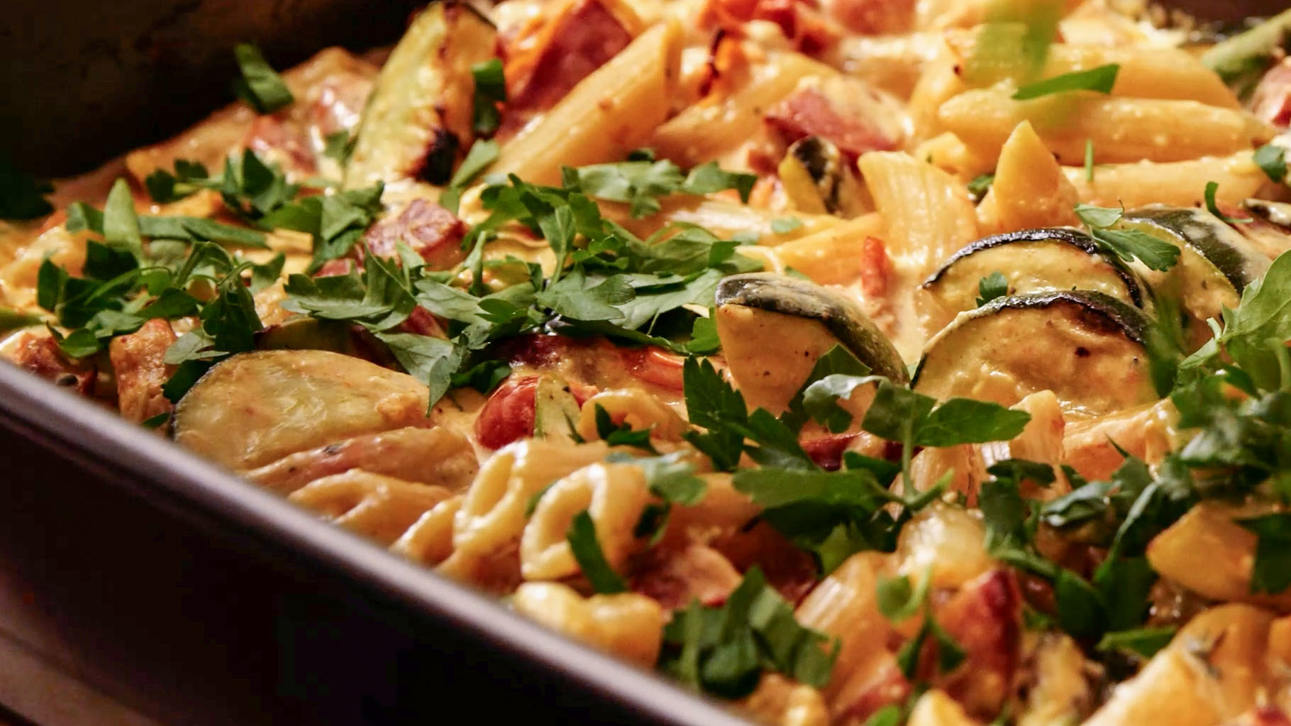 Baked pasta dish with vegetables and garnished with herbs in a baking tray