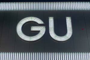 Illuminated 'GU' logo on a dark background with decorative horizontal lines above and below