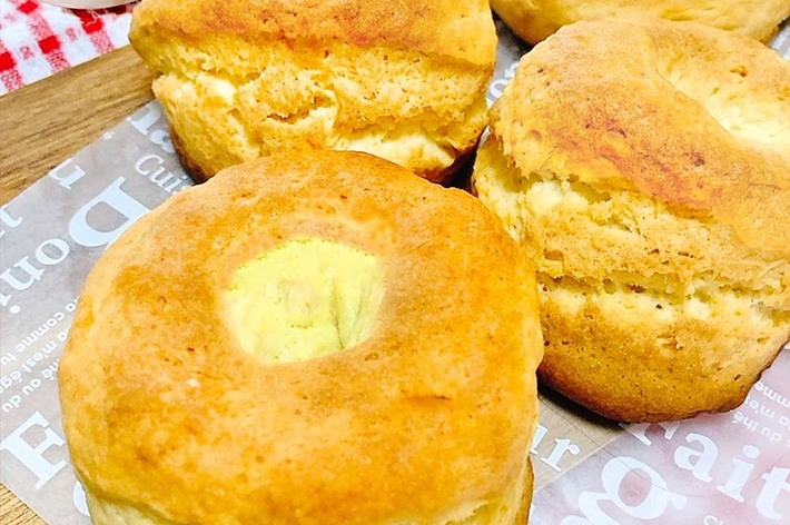 新聞の上に置かれた四つのスコーンとハチミツポット。