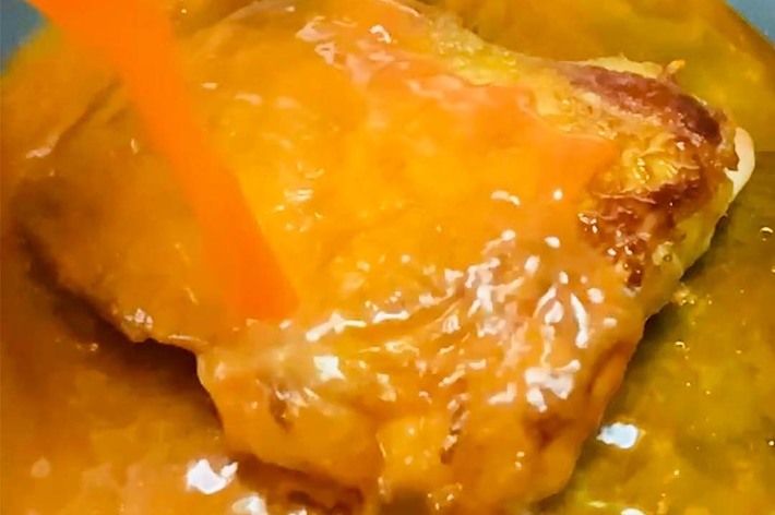 オレンジ色のソースをかけられているチキンの胸肉。