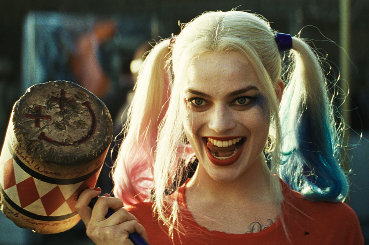 Harley Quinn smiles holding a bat, dressed in a jester-inspired outfit with pigtails