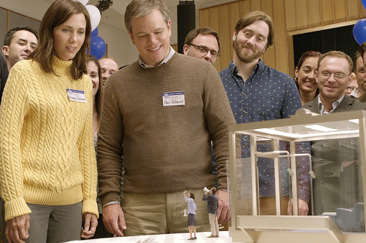 Group of people admiring a miniature architectural model, including characters Mark and Vanessa from the movie &#x27;Juno&#x27;