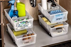 Assorted cleaning supplies organized in labeled white bins under a sink