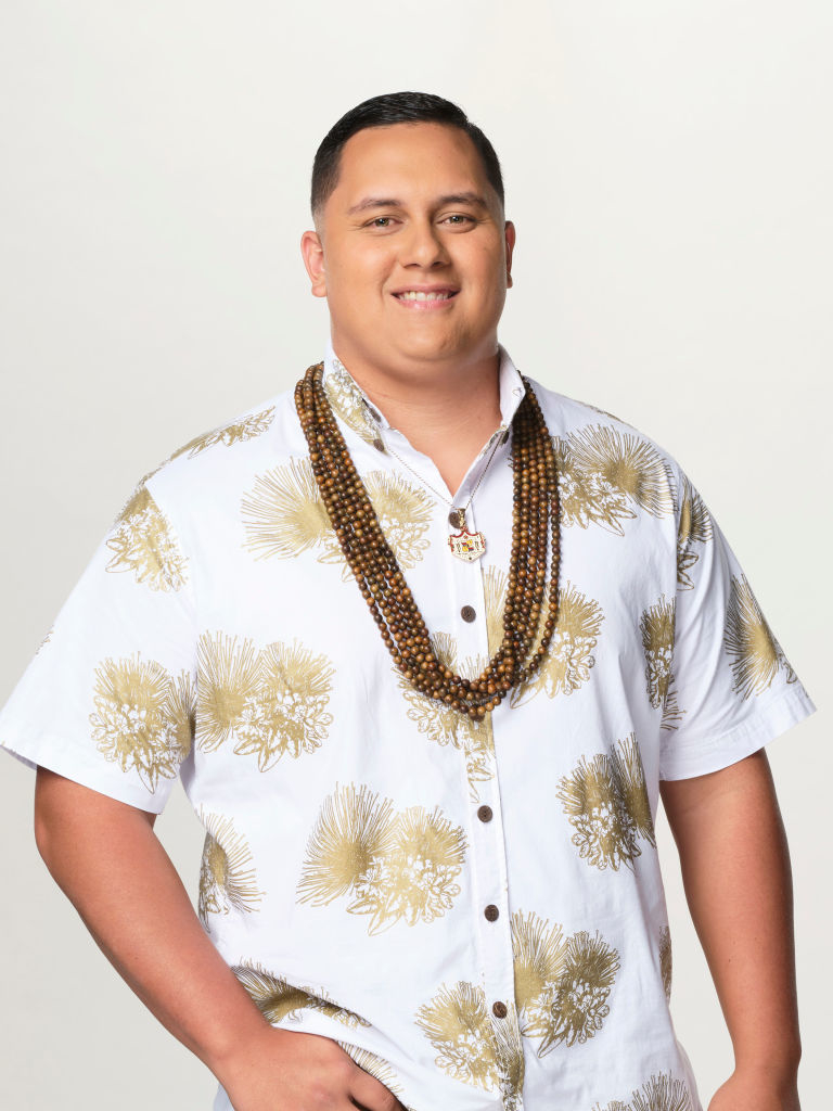 Man in printed shirt with necklace, posing for the photo