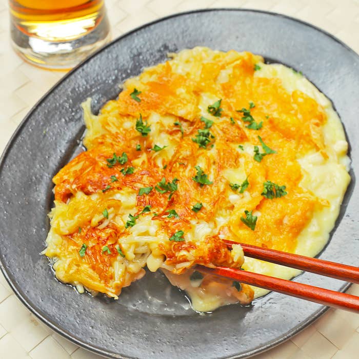 黒い皿に盛られたチーズえのき。箸で一部が持ち上げられている。