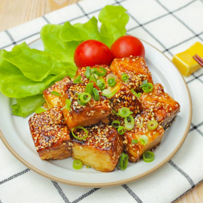 皿に盛られたごまとネギがトッピングされた厚揚げ料理。