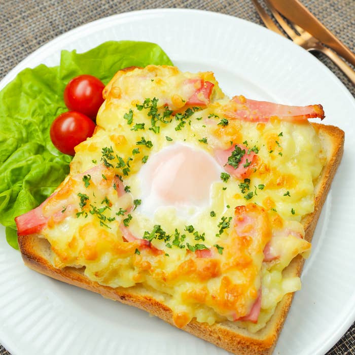 トーストの上に目玉焼きがのった朝食プレート、添えられたレタスとトマト付き。