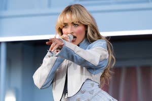 Person performing on stage with a microphone, wearing a stylized jacket and pants
