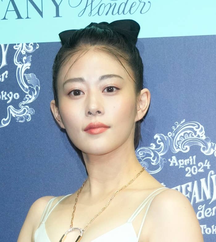 女性がイベントでヘアバンドを着用し、白いドレスを身に着けています。