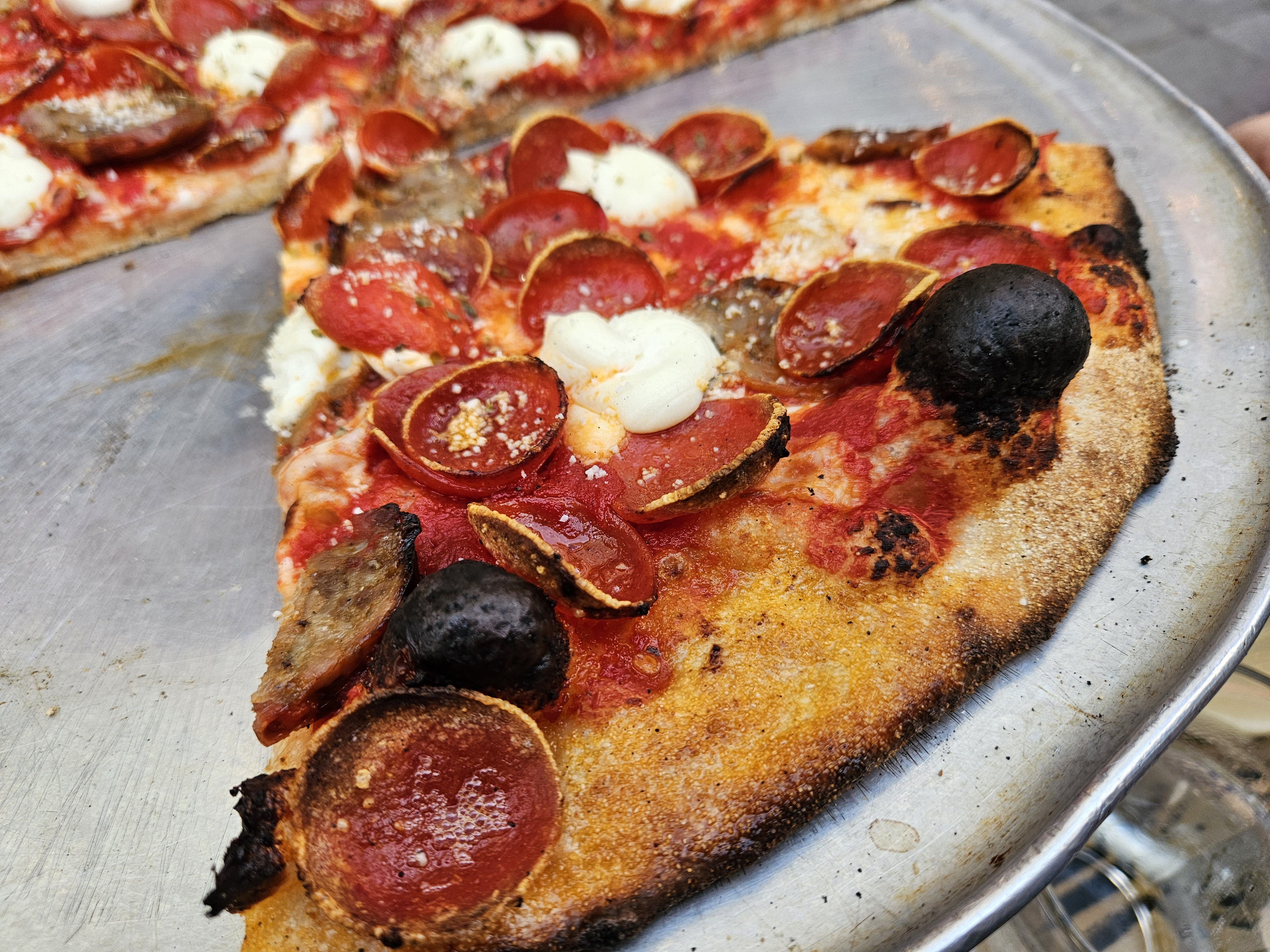 Sliced pepperoni pizza with olives on a metal tray