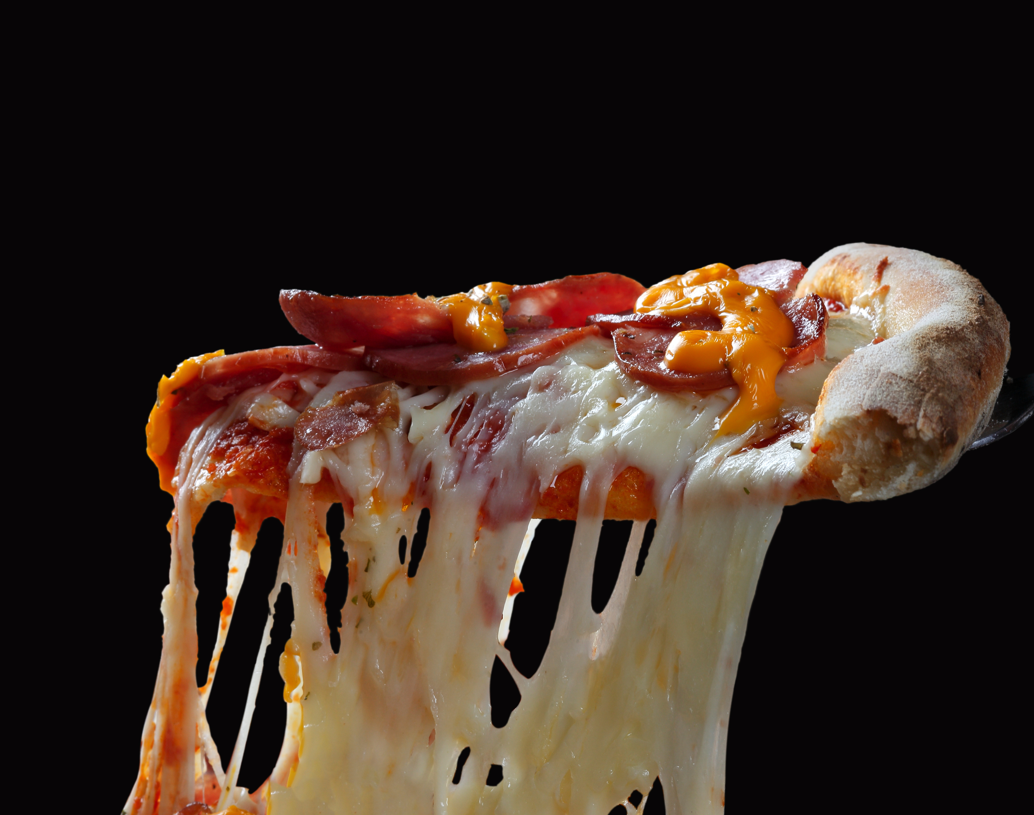 Slice of pizza with melted cheese and pepperoni being lifted, cheese stretching