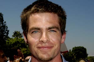Chris Pine in striped shirt smiling at an outdoor event