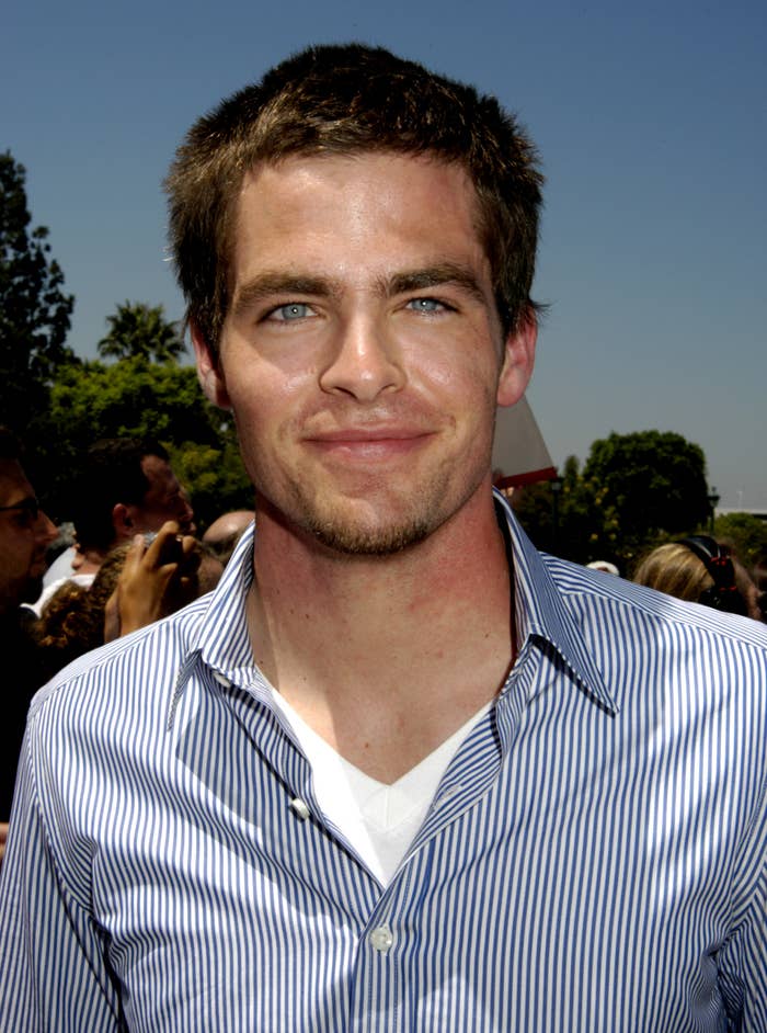 Chris Pine in striped shirt smiling at an outdoor event
