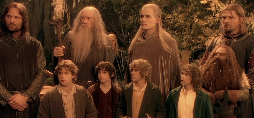 Characters from 'The Lord of the Rings' including Frodo, Sam, Gandalf, Legolas, and Aragorn standing together outdoors