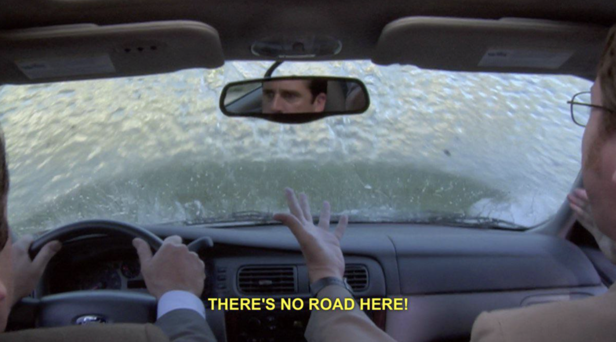Scene from a TV show with a character driving into a body of water, hands raised, text: &quot;THERE'S NO ROAD HERE!&quot;