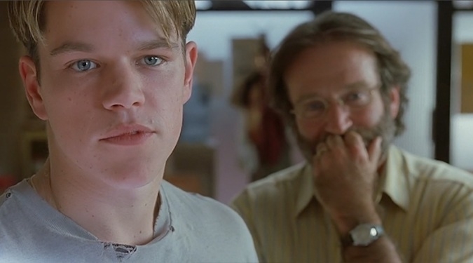 Two characters from the film "Good Will Hunting": a young man in the foreground and an older man behind him with a hand over his mouth