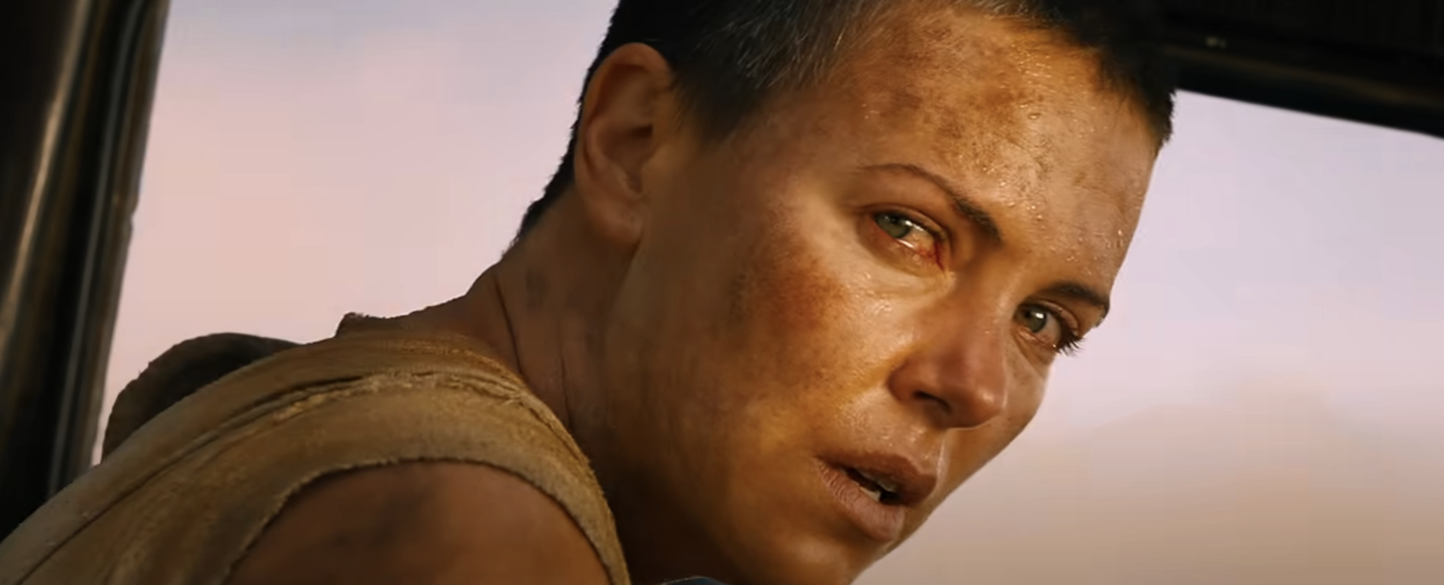 Furiosa, a character from Mad Max, looks intently through a vehicle&#x27;s window