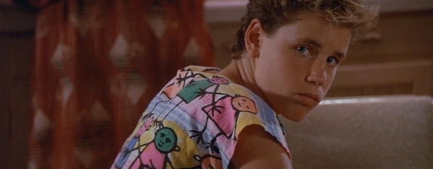 Person in patterned shirt looking over shoulder indoors