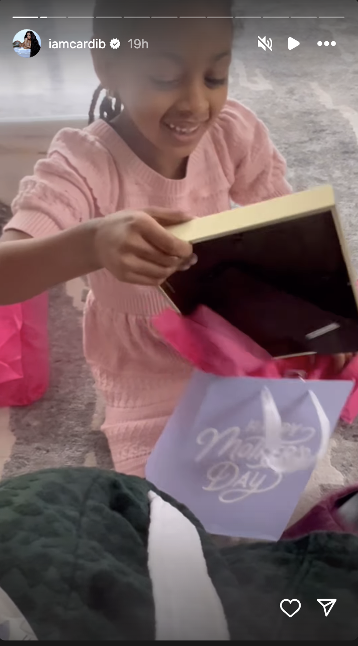 Child smiling and opening a Mother’s Day gift, with a visible greeting card