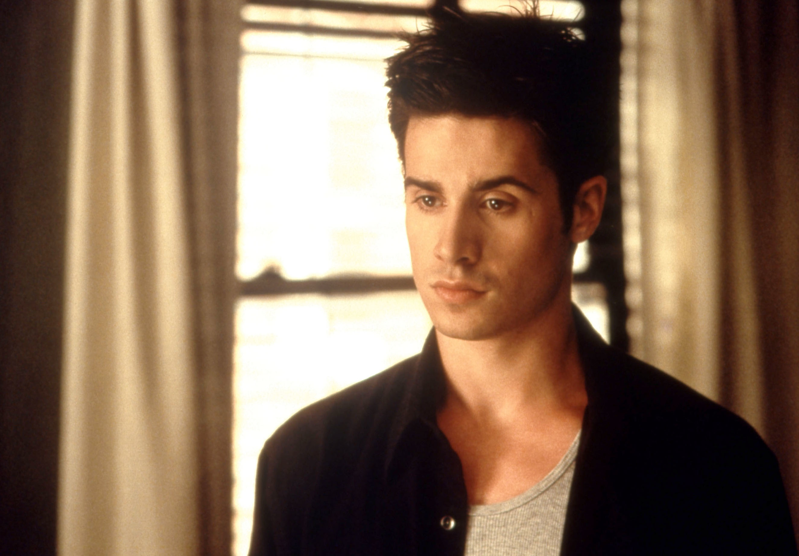 in a scene, Freddie with a contemplative look, in a dark shirt layered over a lighter one