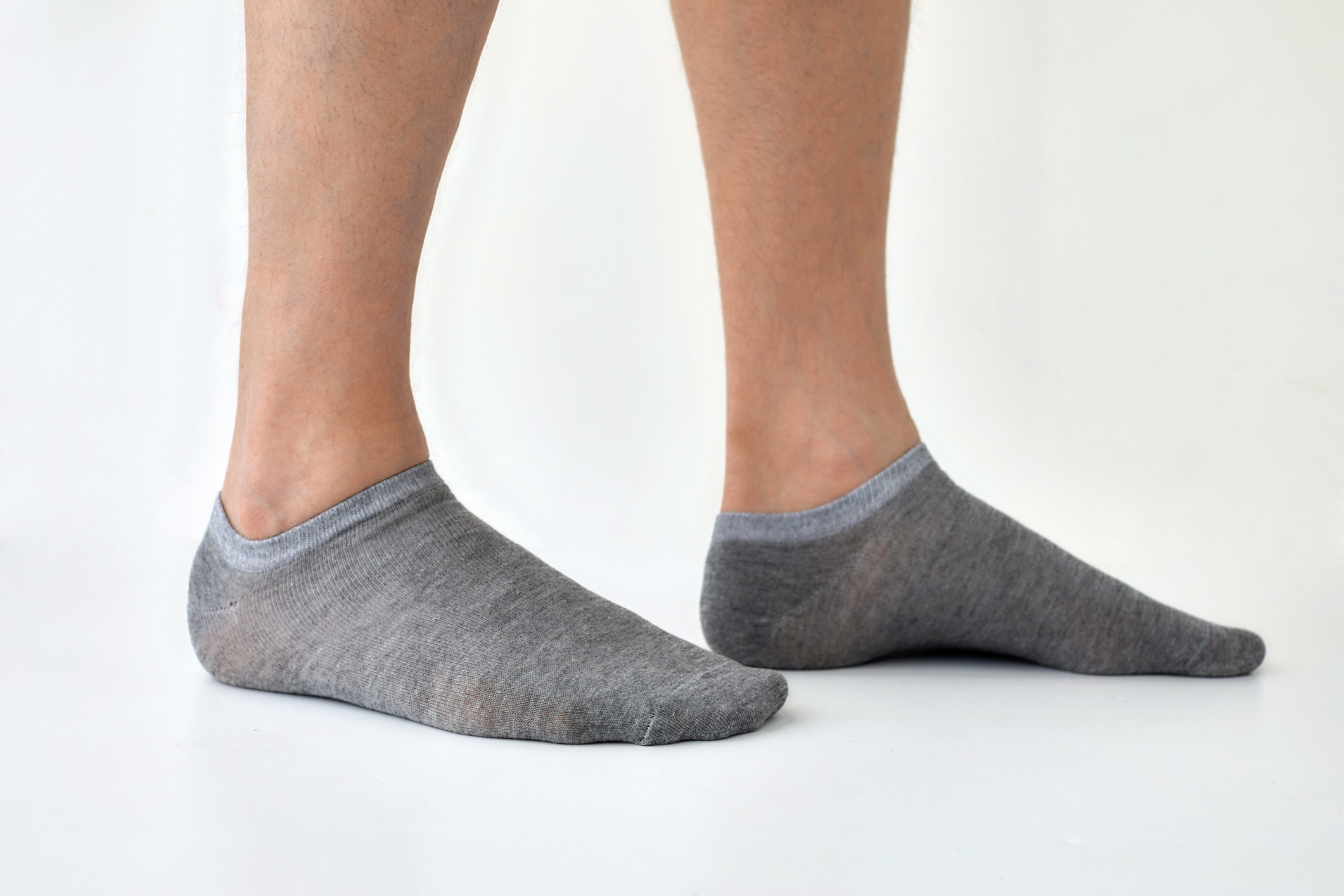 Person standing in no-show socks against a white backdrop
