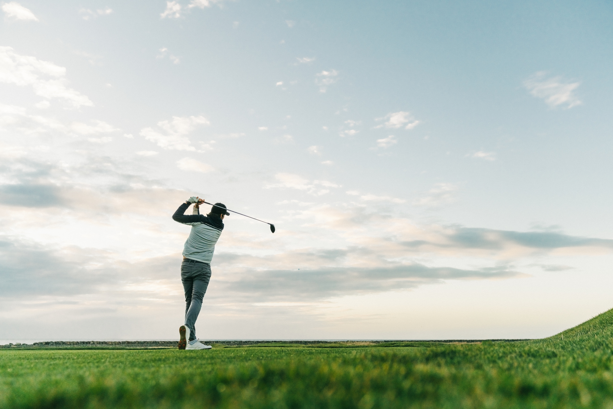 Person swinging a golf club on a course at dusk