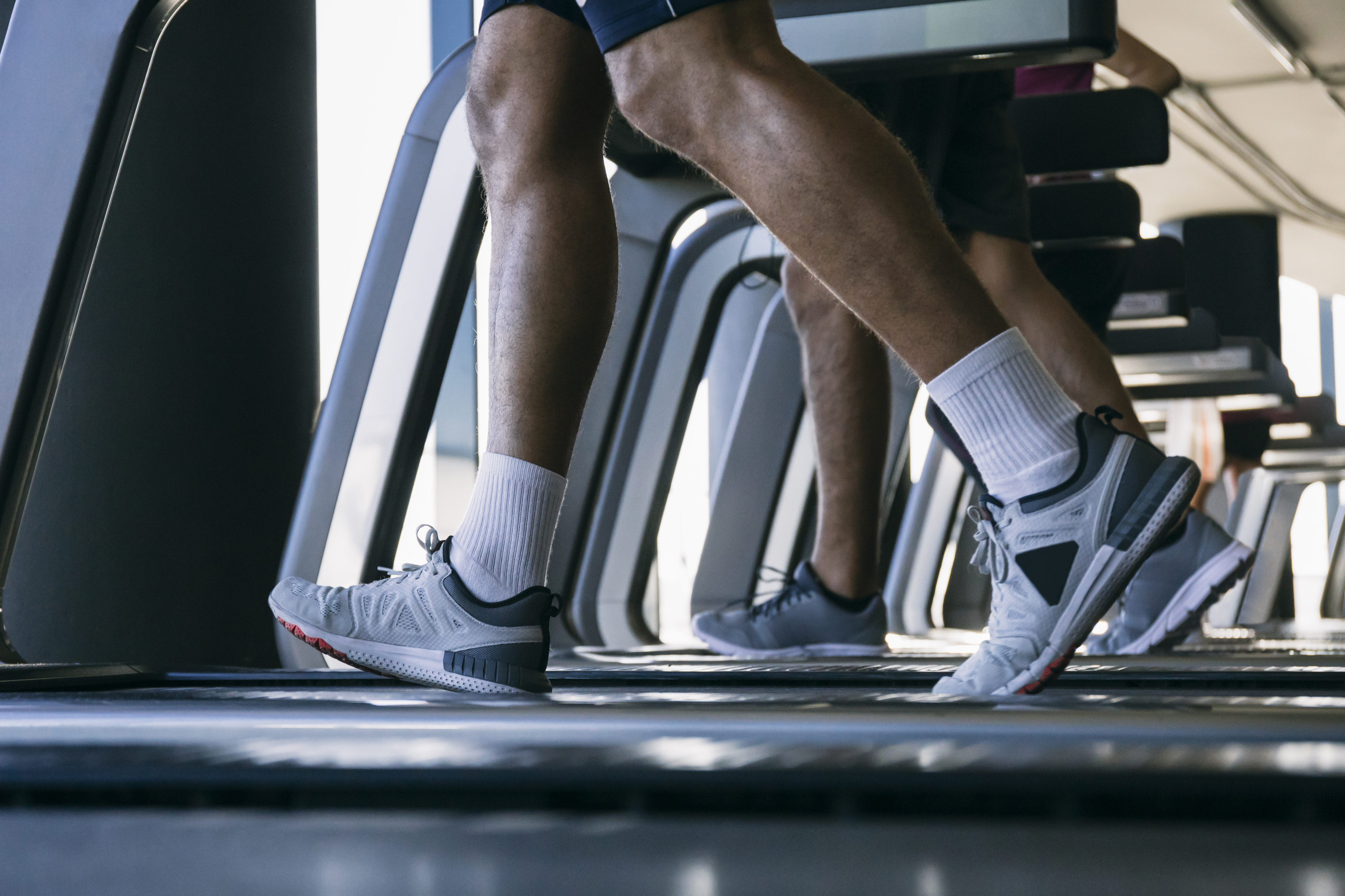 Person exercising on a treadmill, focusing on their legs and sneakers