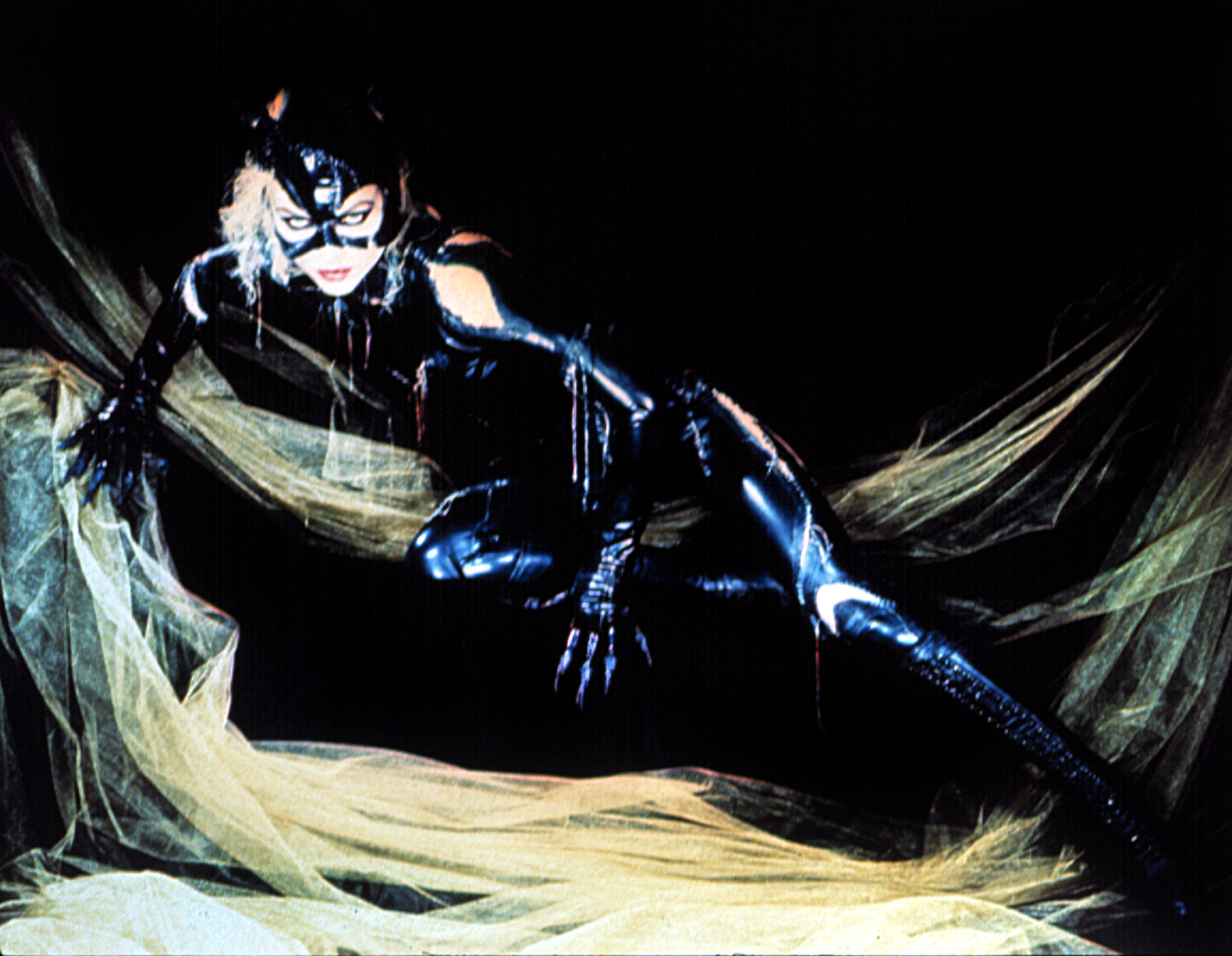 Catwoman character portrayed by Michelle Pfeiffer in a vinyl costume with a whip, posed dynamically against a dark backdrop