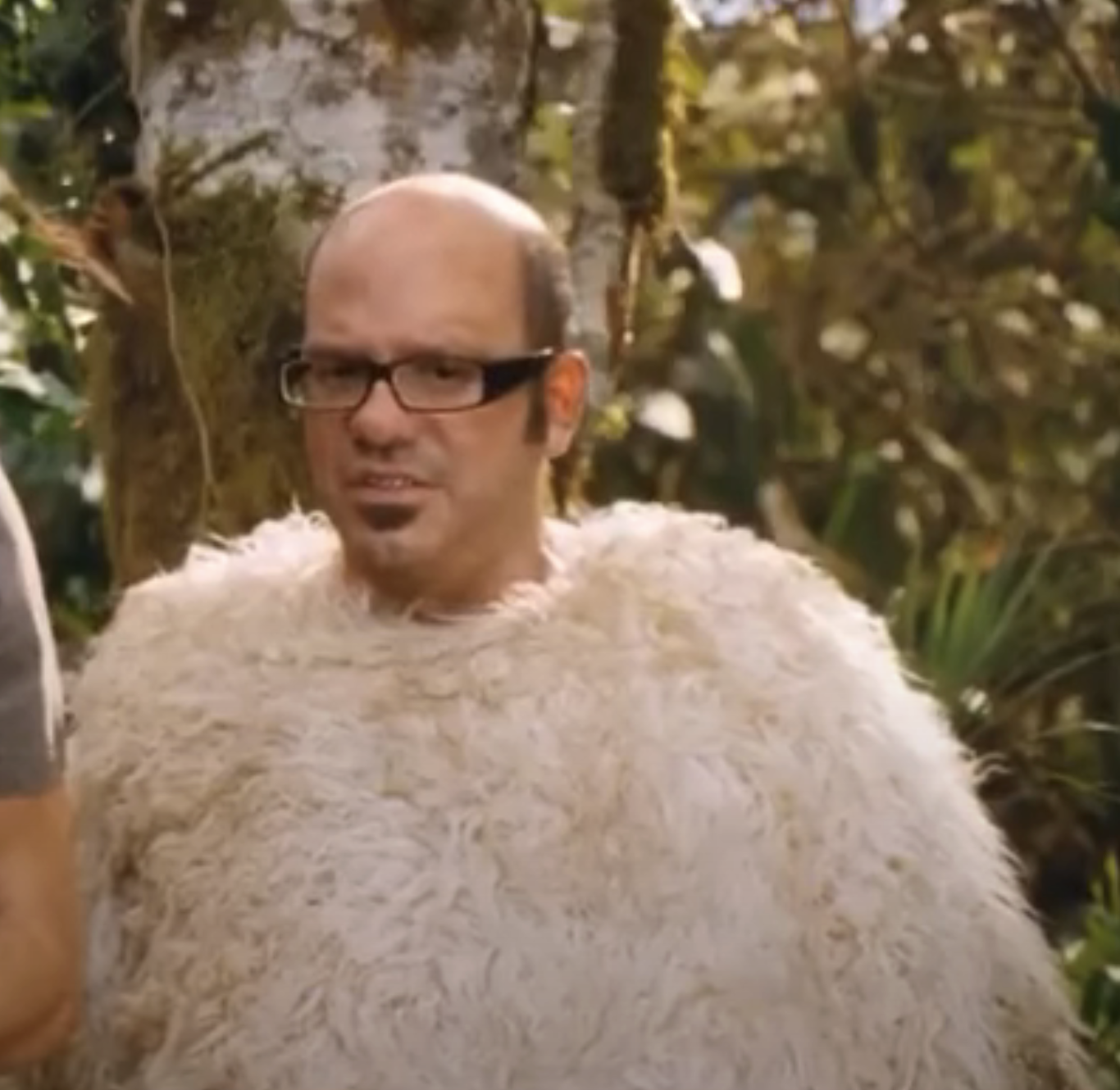in a scene, David as Ian in glasses wearing a fluffy costume resembling a bird, outdoors