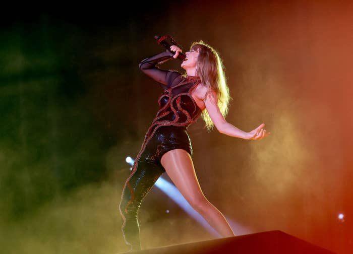 Taylor Swift singing on stage, wearing a sparkly one-legged bodysuit