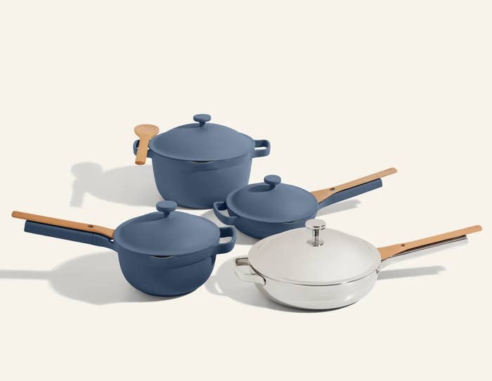 blue cookware set with two pots and two pans, each with wooden spoons