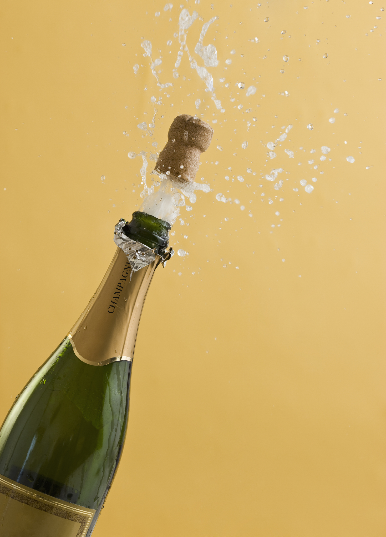 Champagne bottle with cork popping and liquid spraying out against a plain background