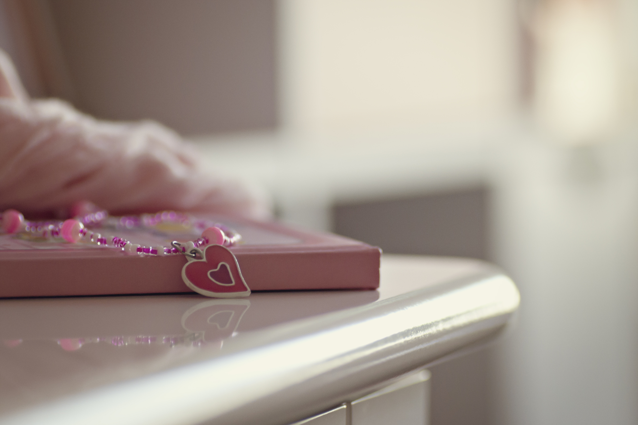 Pink diary with a beaded bookmark on a white surface