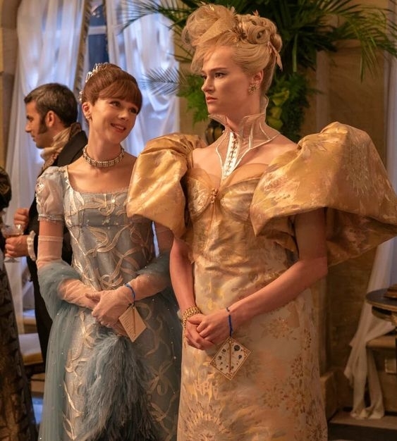Personajes de Bridgerton en vestidos de época con adornos y peinados elegantes