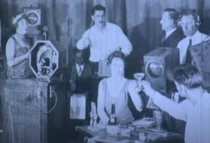 Vintage photo of people toasting at a gathering with an old-fashioned camera present