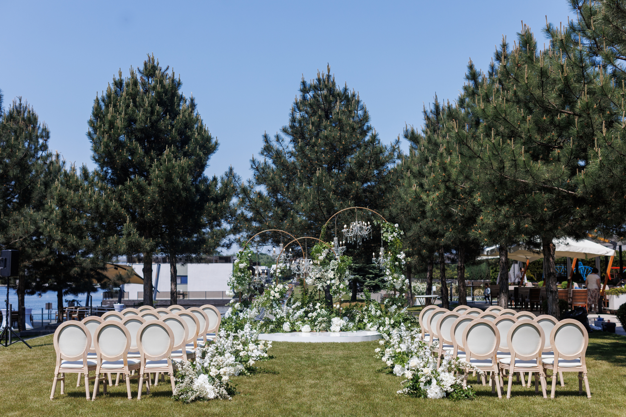 Outdoor wedding setup with white chairs and floral decorations, no individuals present