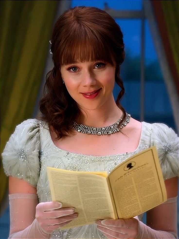 Personaje Elsa de Frozen sosteniendo un libro, con vestido de estilo época y collar de pedrería