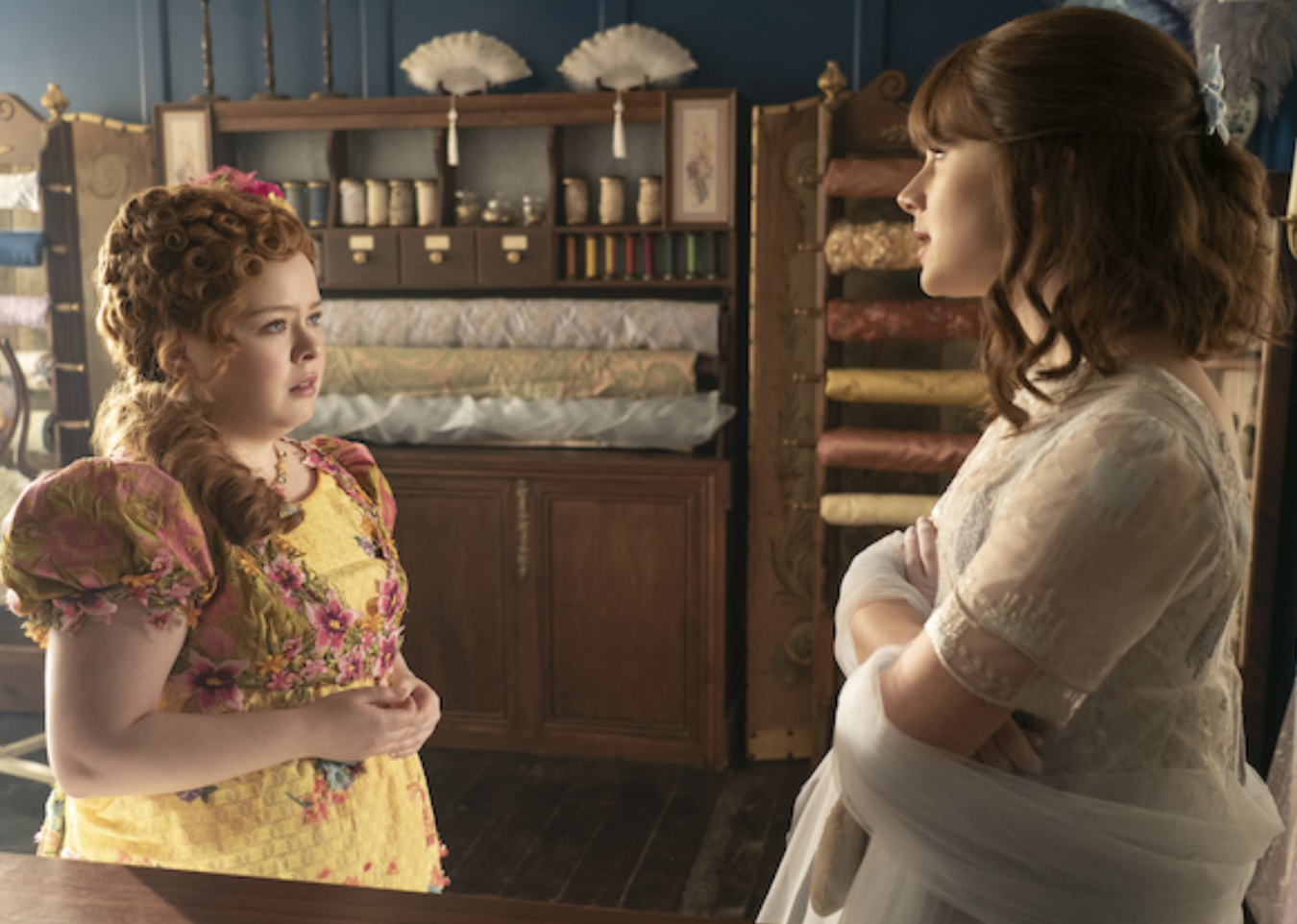 Personajes de Bridgerton conversando en una tienda de modas del período de Regencia