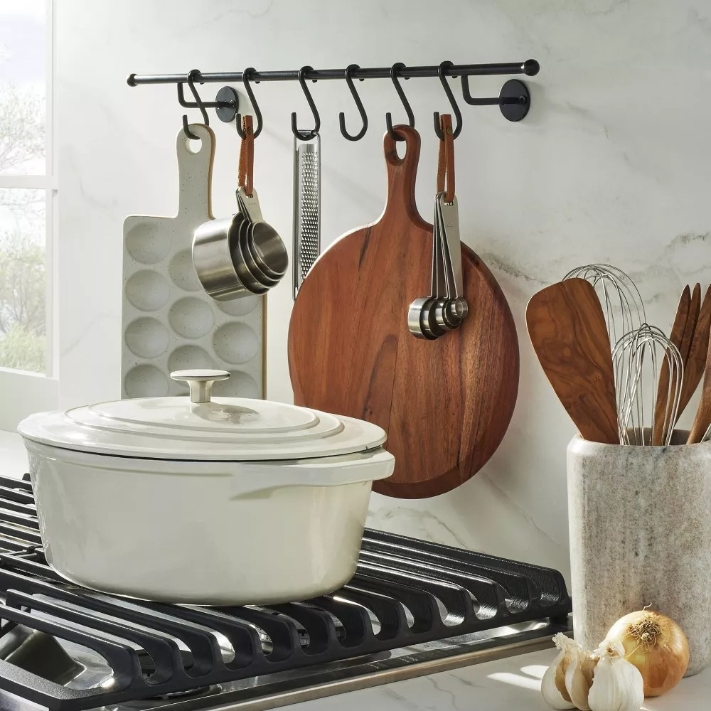 Kitchen utensils and a pot hanging on a rail above a stove