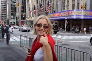Emma Chamberlain giving a thumbs up with Radio City Music Hall in the background