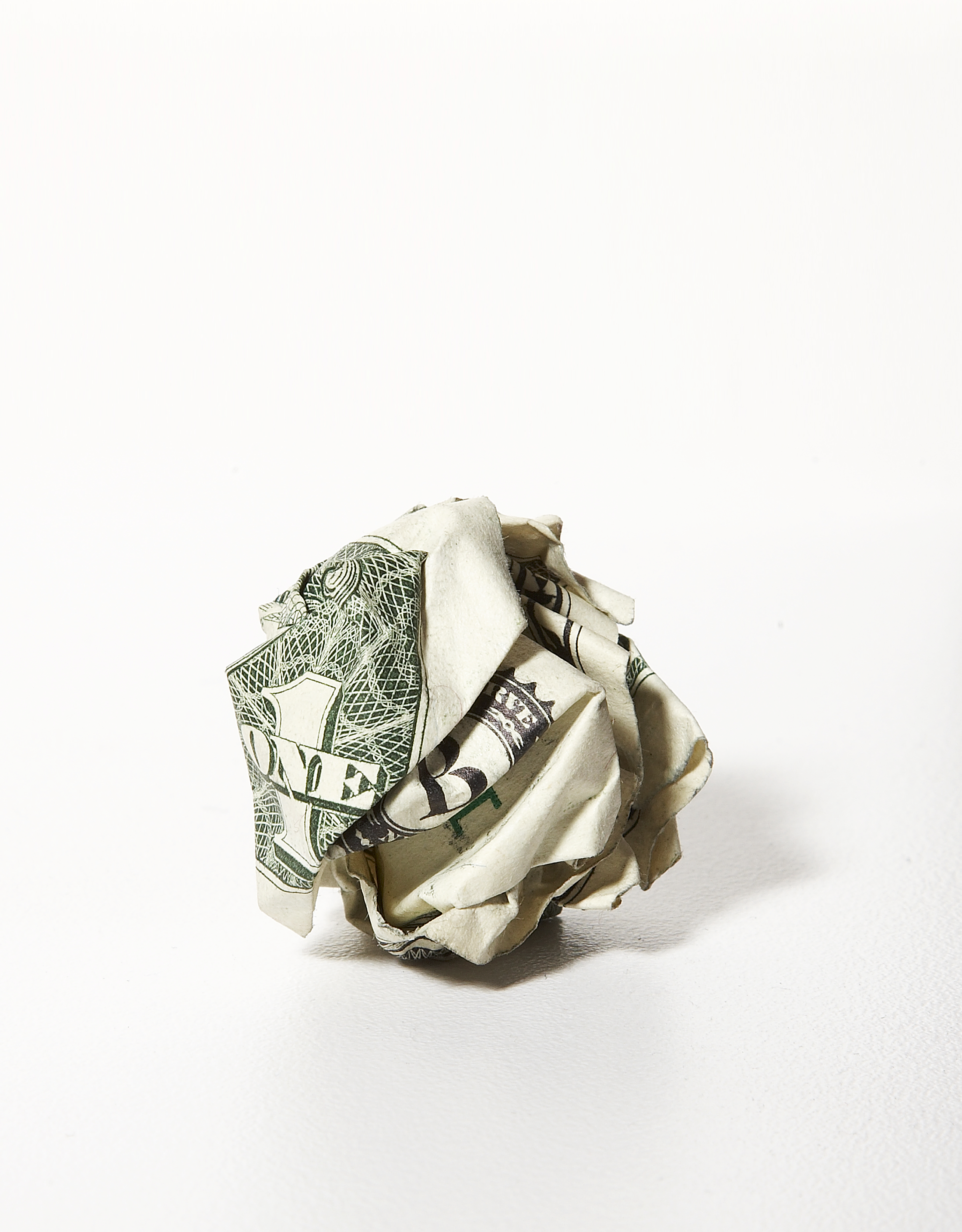 Crumpled US one-dollar bill on a plain background, symbolizing financial distress or loss