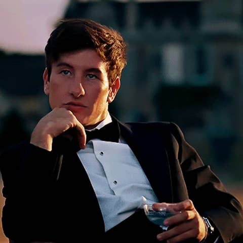 Man in formal attire sits thoughtfully with a glass in hand, suggesting themes of success or contemplation in a work context