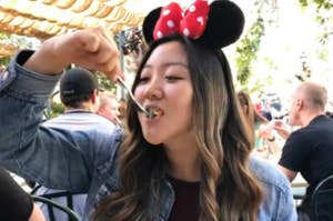 Person wearing Minnie Mouse ears eating at a theme park