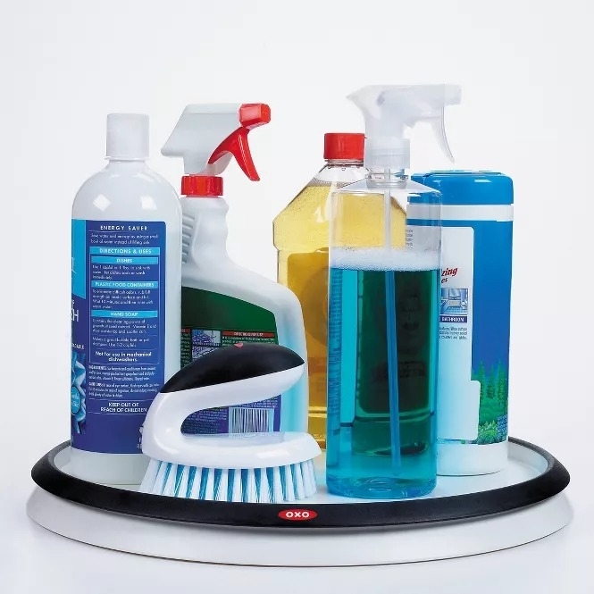 Various cleaning supplies, including spray bottles and a scrub brush, arranged on a turntable organizer