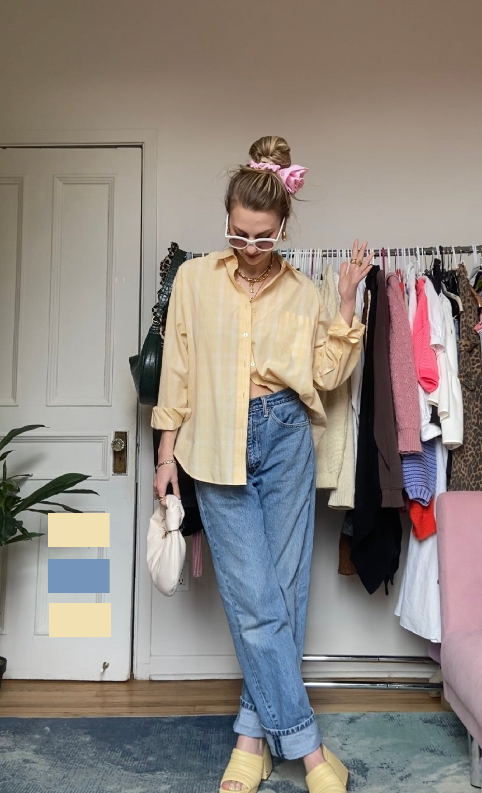 Person in a casual outfit with a yellow top, jeans, and sunglasses, posing in a room with a clothing rack