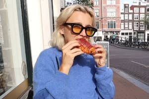 Emma Chamberlain eating a chocolate croissant outside